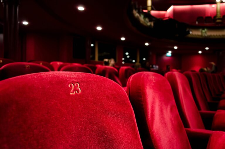 Rows of red velvet seats in a softly lit cinema